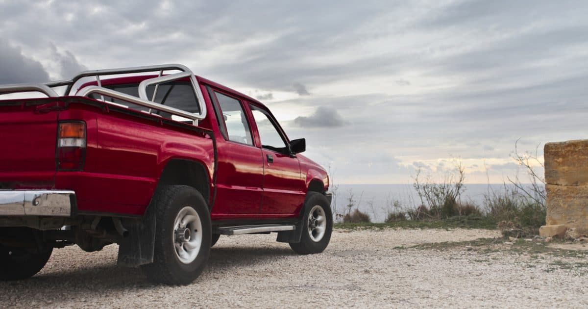 A red pickup truck parked by the water