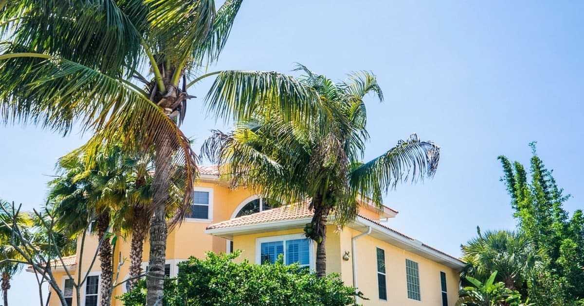 A yellow house surrounded by palm trees