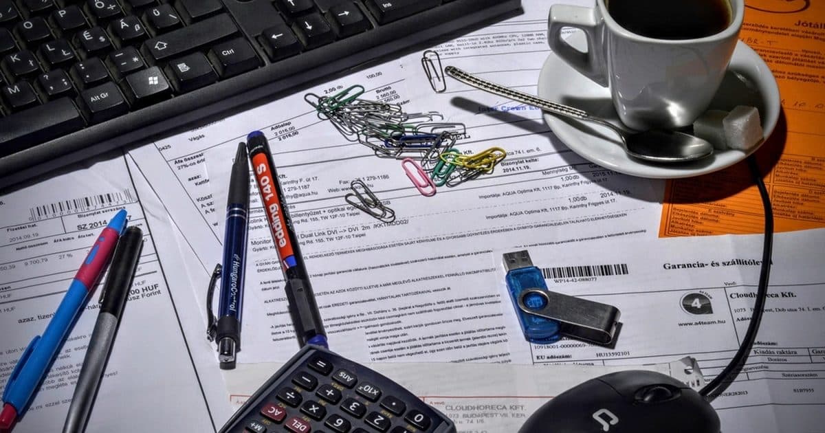 Invoices, pens and a calculator on a desk