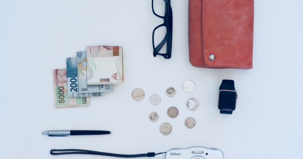 Banknotes, coins and a wallet laid out on a white surface